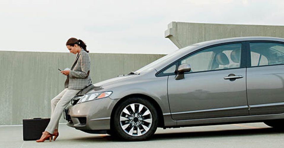 Businesswoman texting on mobile phone in car park